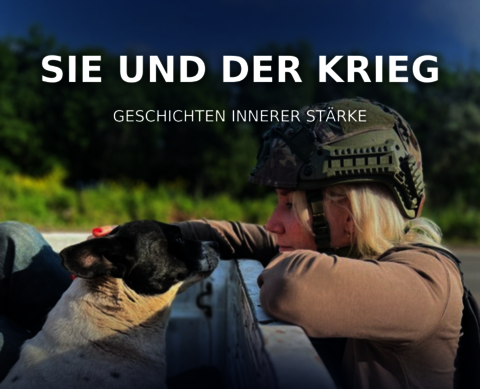 Soldatin an einem Zaun streichelt einen Hund.