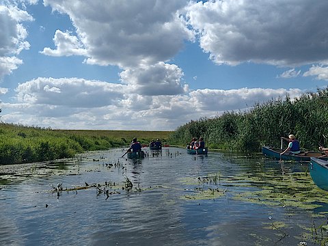 Eine Gruppe von Kanus bei einer Paddeltour auf einem Fluss.